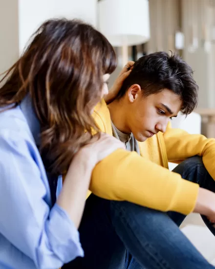 A care worker consoling a teenage boy in his room