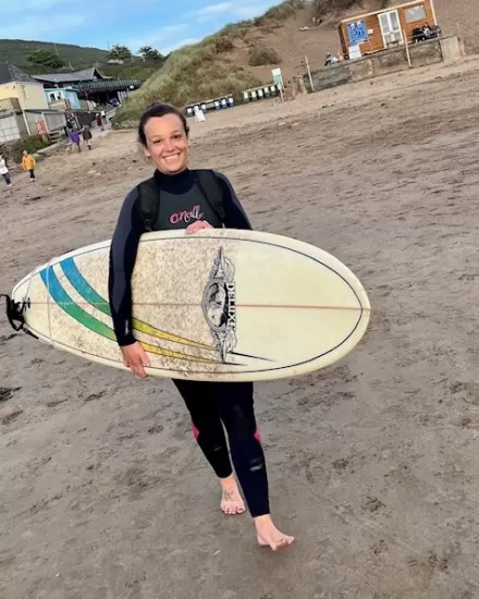 Tina holding a surfboard at Saunton Beach