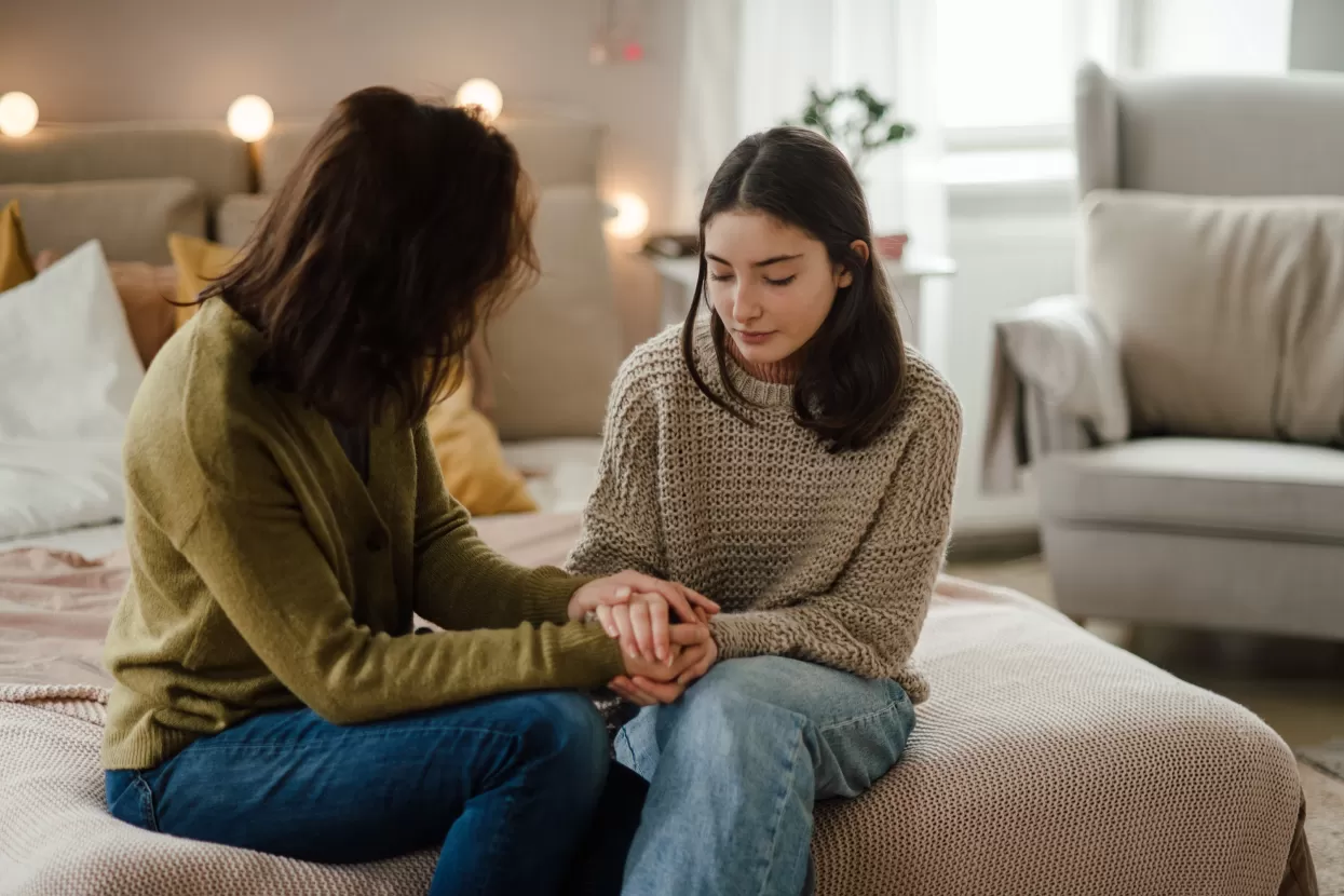 A care worker consoling a teenage girl in her room