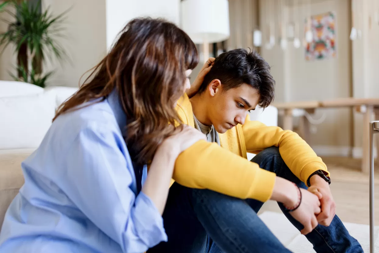 A care worker consoling a teenage boy in his room