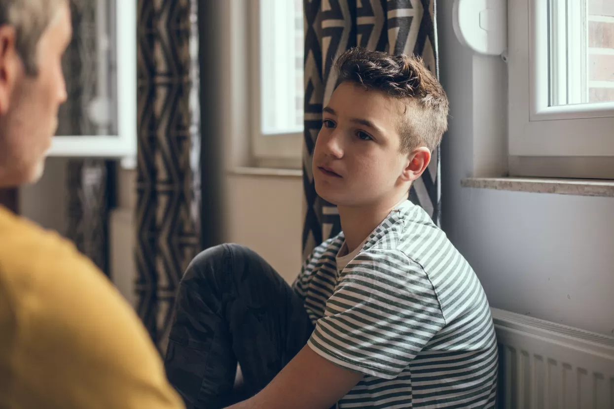 Young teenage boy talking to adult