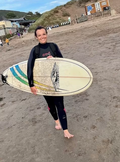 Tina holding a surfboard at Saunton Beach