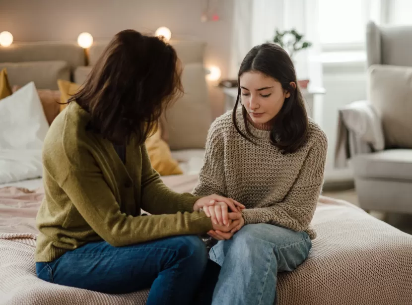 A care worker consoling a teenage girl in her room