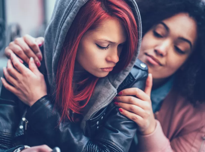 A care worker comforting a distressed teenage girl