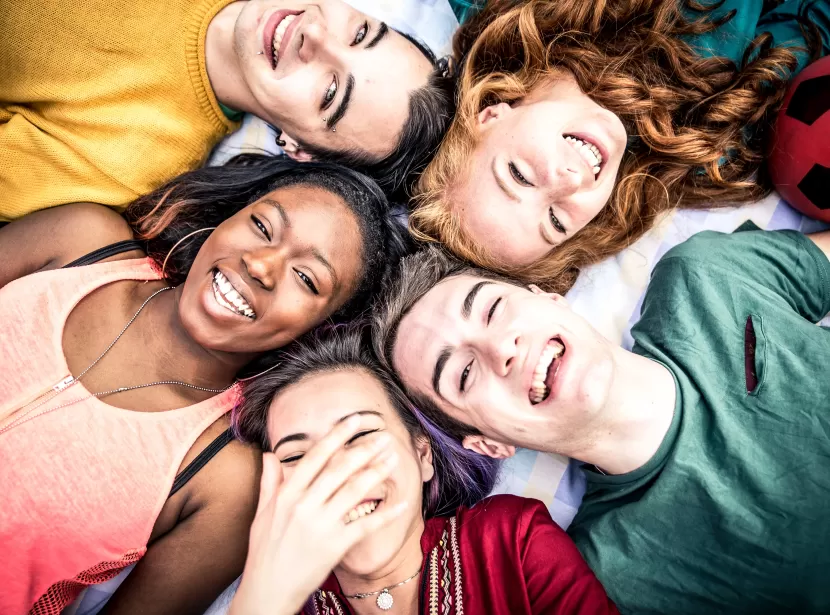 A group of happy young people lying down in a circle